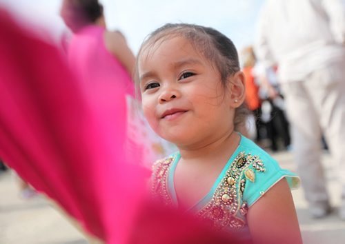 Two year old Tatianna Rosario waves her giant pink in traditional filipino dress while attending the Filipino Street Festival held in the parking lot of Garden City Shopping Centre Saturday.  The event runs until 9pm Saturday night. August  24,, 2013 Ruth Bonneville Winnipeg Free Press