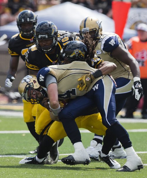 Winnipeg Blue Bombers quarterback Buck Pierce (front) gets sacked by Hamilton Tiger-Cats Rico Murray, as Tiger-Cats Eric Norwood (2nd L) moves to the play during the second half of their CFL football game in Guelph, August 24, 2013.  REUTERS/Mark Blinch (CANADA - Tags: SPORT FOOTBALL) - RTX12VF6