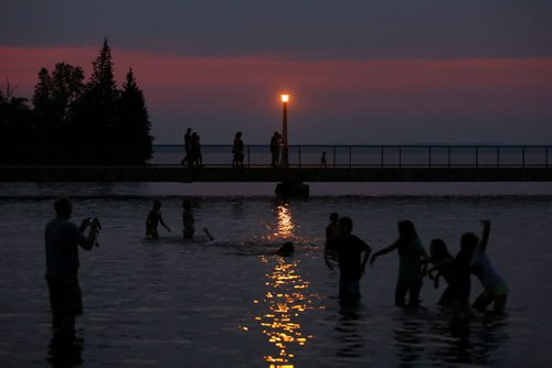 Brandon Sun 24082013 Kids play in the water of Clear Lake or pose for a photo while people stroll along the pier after sunset on a muggy Saturday evening.  (Tim Smith/Brandon Sun)