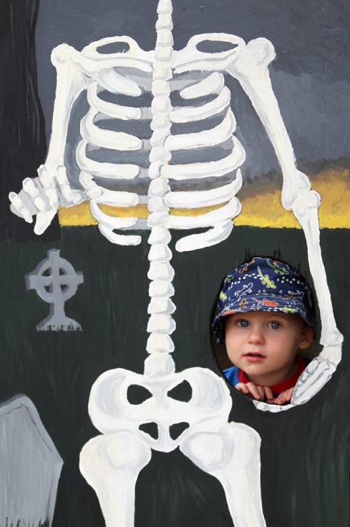 Brandon Sun 24082013 Two-year-old Tavis Fraser peers out from a cutout in a spooky mural  during Boo in the Park in Wasagaming on Saturday. (Tim Smith/Brandon Sun)