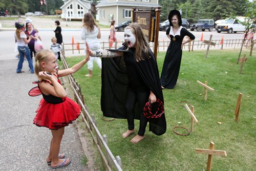 Brandon Sun 24082013 Seven-year-old Olivia Zimmer gets a high-five from a vampire while visiting Hotel Transylvania at the Friends of Riding Mountain National Park building during Boo in the Park in Wasagaming on Saturday. (Tim Smith/Brandon Sun)