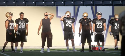 Defensive team members check out drills from the sidelines against the glare of the setting sun at a Bison workout Monday at Investor's field. See story. August 26, 2013 - (Phil Hossack / Winnipeg Free Press)