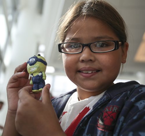 Nine-year-old Tanesha Sinclair shows off a minion she made out of plasticine for a diorama made by 160 youth from the Youth Agencies Alliance. The display, which went up at the Winnipeg Airport today, showcases buildings and spaces that youth want to change or highlight in Winnipeg neighbourhoods. Friday, August 30, 2013. (JESSICA BURTNICK/WINNIPEG FREE PRESS)