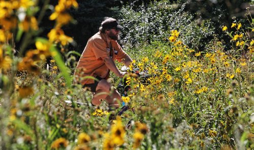 Paul Klimchak rides his bicycle through the butterfly garden at The Forks Monday afternoon.   130902 September 02, 2013 Mike Deal / Winnipeg Free Press