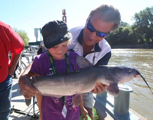 Eight year old Rhyanna Davies doesn't  know what to make of the 30 inch fish she snagged on her line during the Urban Fishing Derby held at the Forks Saturday.  Her dad (not in picture) helped her reel it in and Derby judge Craig McGrath gives her a closer look at the fish just before he throws it back into the river.   Standup photo Sept 07,, 2013 Ruth Bonneville Winnipeg Free Press