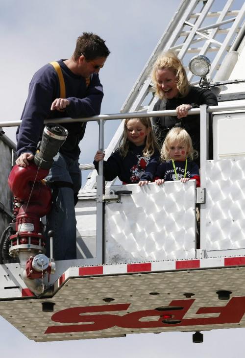 John Woods / Winnipeg Free Press / May 19/07- 070519  - Ava (L) and her sister Anais  their mum Cara Van De Mosselaer are taken 100 feet in the air in the bucket of the fire departments Bronto ladder by firefighter Casey at an event which celebrated 125 years of fire and rescue service in Winnipeg at the Forks Saturday May 19/07.