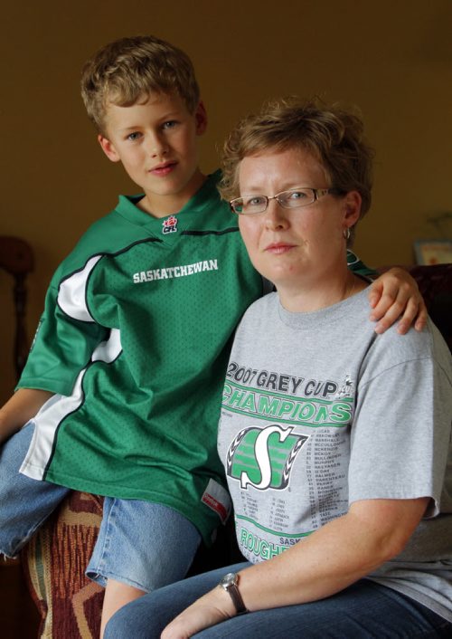 Jodi Montgomery, right, with her son Hugh,8, pose for a photo at their home in Winnipeg. Hugh was victim to a bad Winnipeg Blue Bombers fan at the Banjo Bowl. Sinclair story. BORIS MINKEVICH / WINNIPEG FREE PRESS. Sept. 11, 2013