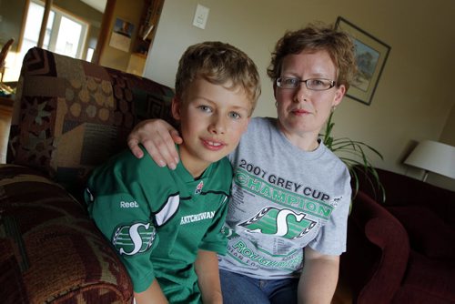 Jodi Montgomery, right, with her son Hugh,8, pose for a photo at their home in Winnipeg. Hugh was victim to a bad Winnipeg Blue Bombers fan at the Banjo Bowl. Sinclair story. BORIS MINKEVICH / WINNIPEG FREE PRESS. Sept. 11, 2013