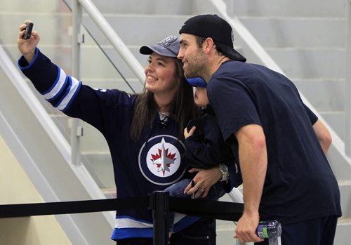 Sports. Jet fan Danica Charriere holding Kingston Fowke,2, (Danica is his nanny) gets a photo with Captain Andrew Ladd after the first day of Winnipeg Jets training camp held at the MTS Iceplex Thursday morning.  Ed Tait story Wayne Glowacki / Winnipeg Free Press Sept. 12 2013