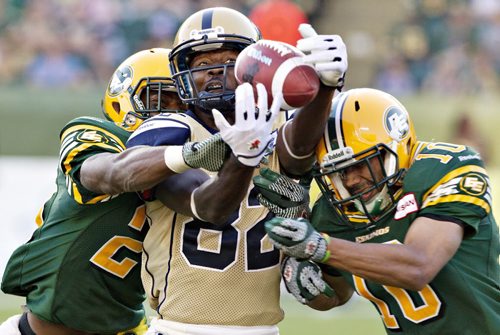 Winnipeg Blue Bombers' Terrence Edwards #82 misses the catch as Edmonton Eskimos' Marcell Young #23 and Donovan Alexander #10 defend during second half action in Edmonton, Alta., on Saturday September 14, 2013. THE CANADIAN PRESS/Jason Franson