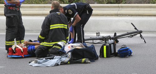 Winnipeg Fire Paramedics attend to an injured male cyclist after he collided with a vehicle on the turn off on the Disraeli Fwy. near Main St. Wednesday afternoon.   Wayne Glowacki / Winnipeg Free Press Sept. 18 2013