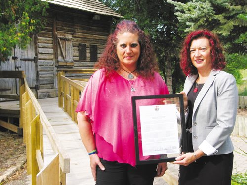 Canstar Community News Sept. 11, 2013 - Sandra Horyski (left) and MLA Sharon Blady (Kirkfield Park) stand in front of Cuthbert Grant's Mill in St. James. Blady presented Horyski with a framed copy of the Member's Statement she read in the Manitoba Legislature on Sept. 9 to recognize Horyski's success in raising money to purchase a memorial marker for her ancestor, Grant. (ANDREA GEARY/CANSTAR COMMUNITY NEWS)