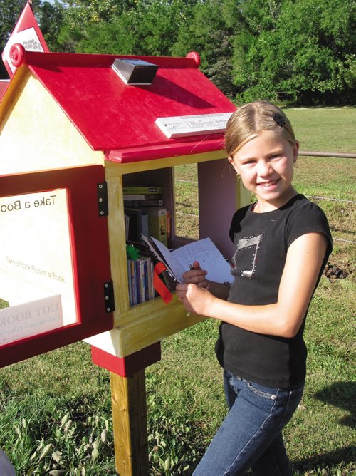 Canstar Community News Sept. 10, 2013 - Meguire McRae-King, 10, checks the notebook to see who took books out of her family's Little Library on Lido Plage Road. (ANDREA GEARY/CANSTAR COMMUNITY NEWS)