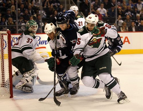 Winnipeg #17 James Wright is sandwiched by Minnesota WIld #4Clayton Stoner and #55 Erik Haula in front of the Wild net in second period action THursday. See story. September 19, 2013 - (Phil Hossack / WInnipeg Free Press)