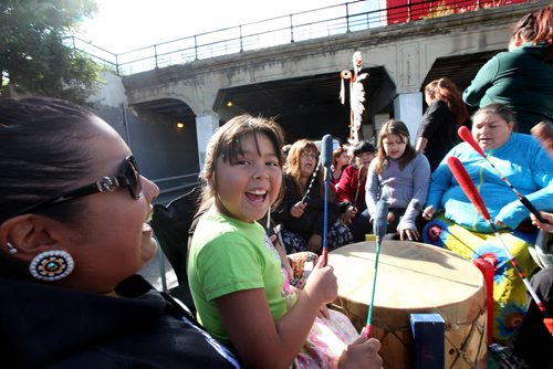 Seven year old Ryleigh Todd-Moore sits on her moms lap while singing and drumming along with a drumming group on a float as the group makes  their way under the Main Street bridge Saturday during the 7th annual Medicine Walk which raises awareness of the abuse of children.    Sept  21,, 2013 Ruth Bonneville Winnipeg Free Press