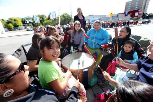 Seven year old Ryleigh Todd-Moore sits on her moms lap while singing and drumming along with a drumming group on a float as the group makes  their way across Main Street Saturday during the 7th annual Medicine Walk which raises awareness of the abuse of children.    Sept  21,, 2013 Ruth Bonneville Winnipeg Free Press