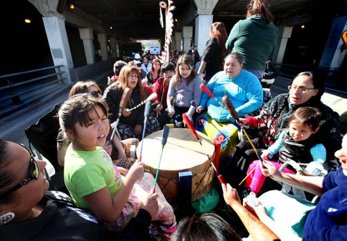 Seven year old Ryleigh Todd-Moore sits on her moms lap while singing and drumming along with a drumming group on a float as the group makes  their way under the Main Street bridge Saturday during the 7th annual Medicine Walk which raises awareness of the abuse of children.    Sept  21,, 2013 Ruth Bonneville Winnipeg Free Press