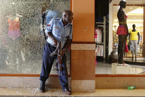 A police officer tries to secure an area inside the Westgate Shopping Centre where gunmen went on a shooting spree in Nairobi September 21, 2013. The gunmen stormed the shopping mall in Nairobi on Saturday killing at least 20 people in what Kenya's government said could be a terrorist attack, and sending scores fleeing into shops, a cinema and onto the streets in search of safety. Sporadic gun shots could be heard hours after the assault started as soldiers surrounded the mall and police and soldiers combed the building, hunting down the attackers shop by shop. Some local television stations reported hostages had been taken, but there was no official confirmation. REUTERS/Siegfried Modola  (KENYA - Tags: CIVIL UNREST) - RTX13TNN