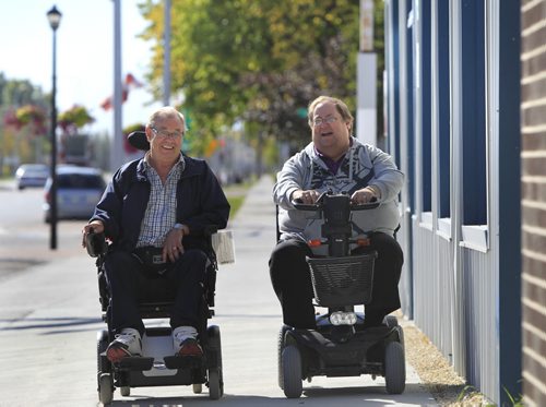 At right, Morris councilor Bruce Third and friend Ron Unrau on the wide sidewalks of downtown Morris on their motorized transportation.  The town of Morris has widened sidewalks to two metres, and installed curb cuts, to accommodate the over 50 mobility scooter and medical chair users in town. Bill Redekop story Wayne Glowacki / Winnipeg Free Press Sept. 24 2013