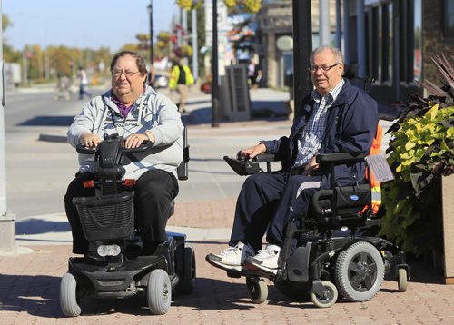 At left, Morris councilor Bruce Third and friend Ron Unrau on the wide sidewalks of downtown Morris on their motorized transportation.  The town of Morris has widened sidewalks to two metres, and installed curb cuts, to accommodate the over 50 mobility scooter and medical chair users in town. Bill Redekop story Wayne Glowacki / Winnipeg Free Press Sept. 24 2013