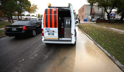 Water flows out of the ground and down the street towards the Assinaboine River at the site of a water main break South of Portage ave at Ferry Road Thursday afternoon. See Aldo Santin story. September 26, 2013 - (Phil Hossack / Winnipeg Free Press)