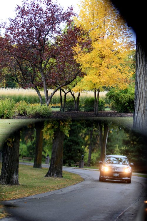 Interesting juxtaposition. Two images both front and from behind appear in the same picture as the photographer shoots both a car making its way through Assiniboine park (seen in the  drivers side mirror) and the contrasting trees in the foreground at Assiniboine Park Thursday afternoon. Standup photo.  Sept  26,, 2013 Ruth Bonneville Winnipeg Free Press