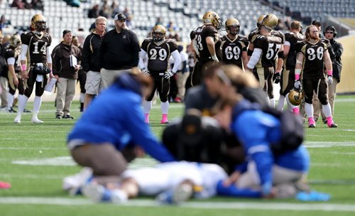 The University of Manitoba Bisons look on while trainers assess UBC Thunderbirds' Miguel Barker, who lay injured on the field for about 30 minutes before being taken away in an ambulance during their game at Investors Group Field, Saturday, October 5, 2013. (TREVOR HAGAN/WINNIPEG FREE PRESS)