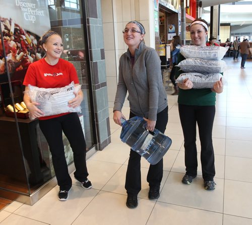 Manager Patty Cox, centre, with employees of the St Vital Booster Juice hauls ice and bottled water purchased so she can open her restaurant- The province of Manitoba ordered a boil water advisory for parts of South East Winnipeg after e coli was detected-See Ashley Prest story- Oct 09, 2013   (JOE BRYKSA / WINNIPEG FREE PRESS)