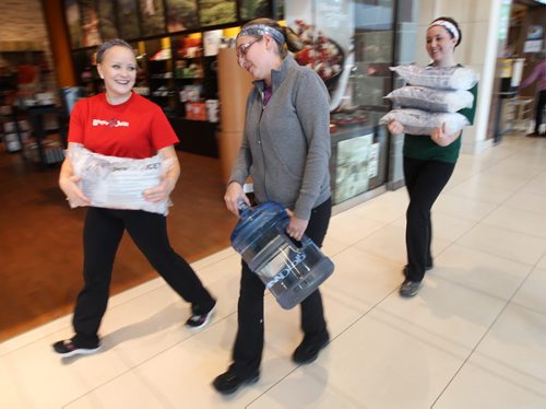 Manager Patty Cox, centre, with employees of the St Vital Booster Juice hauls ice and bottled water purchased so she can open her restaurant- The province of Manitoba ordered a boil water advisory for parts of South East Winnipeg after e coli was detected-See Ashley Prest story- Oct 09, 2013   (JOE BRYKSA / WINNIPEG FREE PRESS)