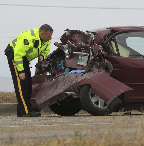 An RCMP officer at the  crash scene of three vehicles that collided with a semi trailer on the south Perimeter Hwy. near Budd Rd. Friday morning.Wayne Glowacki / Winnipeg Free Press Oct. 11 2013
