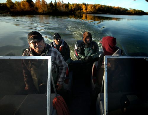 Harvey Bushie (left) steers his boat out onto the calm early morning Lake Winnipeg Waters taking his crew out to an island based fishing camp where they will disperse in different boats to harvest fish. Harvey Bushie and his son Rick harvest fish from the Lake Winnipeg Waters near Hollow Water. October 9, 2013 - (Phil Hossack / Winnipeg Free Press)