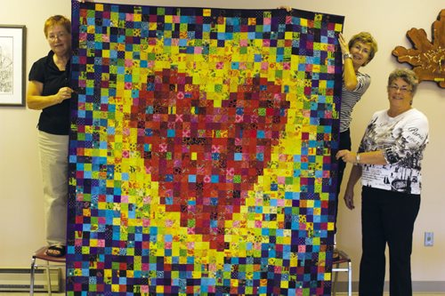 Canstar Community News Fran Howard (left) holds up one of her quilts with help from Material Girls club members Rita Toews and Leone Newton.