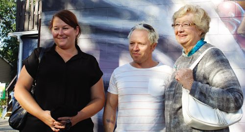 Canstar Community News Sept. 25 -- Mandy van Leeuwen, Michel Saint Hilaire, and Helen Norrie stand in front of the Bill Norrie mural on Ellice and Langside.