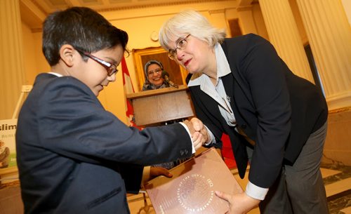 Kaleem Siddiqui, 7, presents Immigration and Multiculturalism Minister Christine Melnick with a Qur'an reference book after she read a proclamation recognizing October as Islamic History Month, at the Manitoba Legislative Building, October 16, 2013. (TREVOR HAGAN/WINNIPEG FREE PRESS)