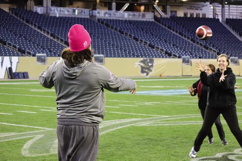 Canstar Community News Bombers fullback Michel-Pierre Pontbriand throws a pass to one of the participants in the 2013 Women's Football Clinic. (JORDAN THOMPSON)