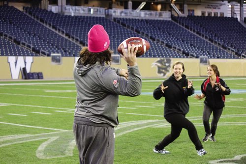 Canstar Community News Bombers fullback Michel-Pierre Pontbriand throws a pass to one of the participants in the 2013 Women's Football Clinic. (JORDAN THOMPSON)