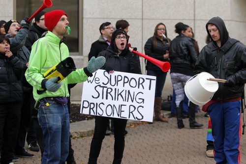 A group called on all concerned citizens and affected families to join them in solidarity to demand the federal government reverse the 30% pay cut to prisoners salaries that took effect earlier this month. Photo taken in front of the Winnipeg Remand Centre. Anne Wyman, centre,  blows her horn during the flash mob. BORIS MINKEVICH / WINNIPEG FREE PRESS  October 23, 2013