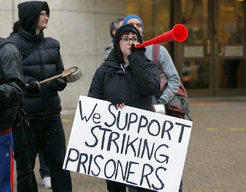 A group called on all concerned citizens and affected families to join them in solidarity to demand the federal government reverse the 30% pay cut to prisoners salaries that took effect earlier this month. Photo taken in front of the Winnipeg Remand Centre. Anne Wyman blows her horn during the flash mob. BORIS MINKEVICH / WINNIPEG FREE PRESS  October 23, 2013