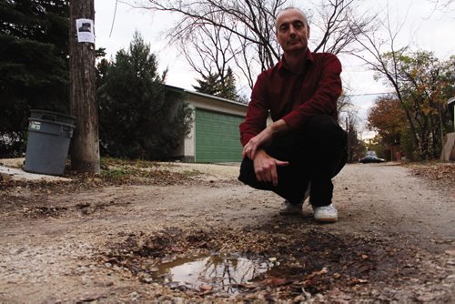 Canstar Community News Paul Christensen with a deteriorating gravel back lane in his neighbourhood. (JORDAN THOMPSON)