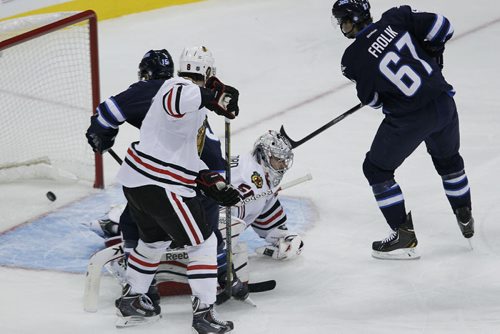 Chicago Blackhawks' goaltender Corey Crawford (50) can't stop this shot from Winnipeg Jets' Toby Enstrom (39) as Jets' Matt Halishchuk (15) and Michael Frolik (67) and Hawks' Nick Leddy (8) look for the rebound during first period NHL action in Winnipeg on Saturday, November 2, 2013. THE CANADIAN PRESS/John Woods