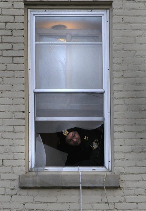 A Winnipeg Police officer sends down a tape measure from a third floor room in the Royal Albert Arms Hotel on Albert St. to an officer below by evidence markers in a vacant lot between the Albert and the St. Charles Hotel Tuesday morning. web story.  Wayne Glowacki / Winnipeg Free Press Nov. 5. 2013
