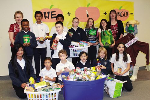 Canstar Community News St. Alphonsus School principal Christine McInnis (back left) and secretary Patti Resendes (back right) with a handful of students who helped compile a shipment of non-perishable food for the K-8 school's We Scare Hunger campaign. (JORDAN THOMPSON)