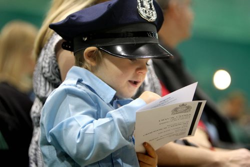 Three year old Larson Gulash dressed in a police uniform smiles as he  finds his dad's name in the list of new recruits during the graduation ceremony for Winnipeg police officer recruit class #154 which took place at the Convention Centre Friday afternoon.    November 15, 2013 Ruth Bonneville / Winnipeg Free Press