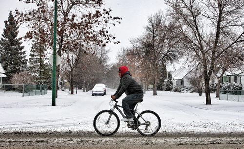 A cyclist makes his way along Mountain Avenue Sunday morning despite the overnight snowfall.  131117 November 17, 2013 Mike Deal / Winnipeg Free Press