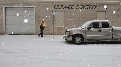 A pedestrian walks by a building with the words Climate Controlled on it during a steady snowfall Sunday morning in Winnipeg's Downtown.   131117 November 17, 2013 Mike Deal / Winnipeg Free Press