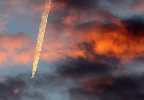 Brandon Sun 19112013 The contrail from a plane soaring over westman cuts a line of vapor through clouds illuminated by the setting sun on Tuesday afternoon. (Tim Smith/Brandon Sun)