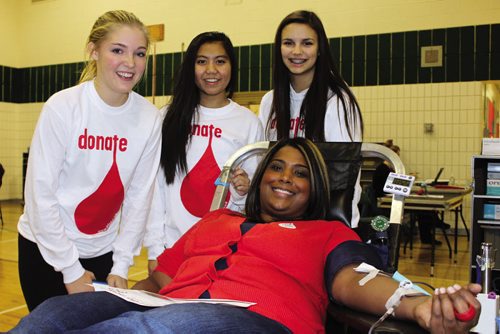 Canstar Community News Melanie Paragg (front) is comforted and encouraged by her Grade 10 students (from left) Shaye Kemball, Patricia Neameyer and Ayla Zimmerman Friday afternoon while donating blood. (JORDAN THOMPSON)