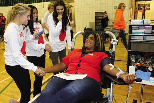 Canstar Community News Melanie Paragg (right) is comforted and encouraged by her Grade 10 students (from left) Shaye Kemball, Patricia Neameyer and Ayla Zimmerman Friday afternoon while donating blood. (JORDAN THOMPSON)