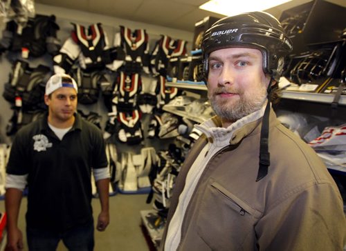 Spartan Sports employee Mike Ducharme, left, with Marcus Malbasa trying on a hockey helmet. The story is about the Jets banning helmets to Chicago game tomorrow night to mock what that drunk guy did to Pardy in Chicago a few weeks ago. Marcus is a Jets fan who doesnt agree with the decision.. BORIS MINKEVICH / WINNIPEG FREE PRESS  November 20, 2013