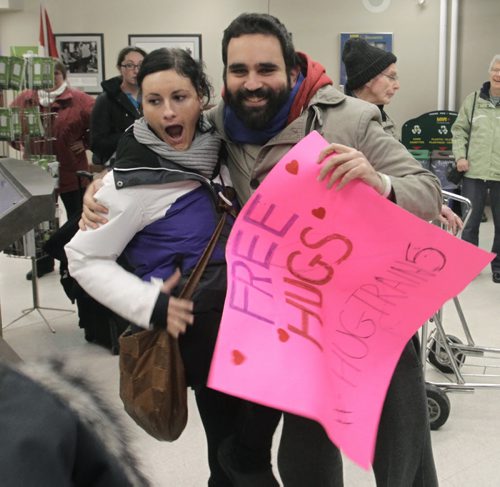 At right, Arié Moyal on his Hug Train 5 cross country train trip arrived in Winnipeg's Union Station Monday morning for a short stop and gives a hug to Anne Maeder on a business trip from Germany. Aria carries a pink sign with the words Free Hugs, his goal is to raise awareness and funds for the Canadian Mental Health Association and brighten spirits during the holidays.  Wayne Glowacki / Winnipeg Free Press Dec.2 2013